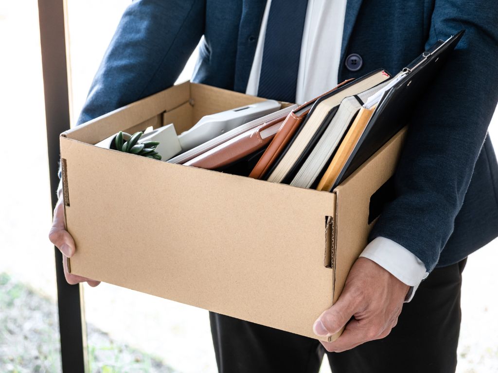 What Is Employment Practices Liability Insurance (Epli) And Why Every Employer Needs It 3 A person in a suit holding a box full of books